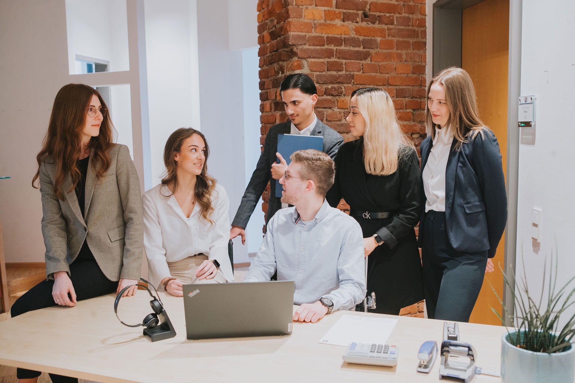 Team steht vor Schreibtisch und spricht miteinander